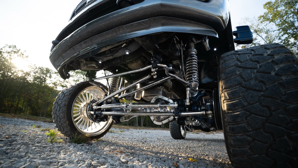 Low angle under the front bumper showing the lift, shocks, and steering