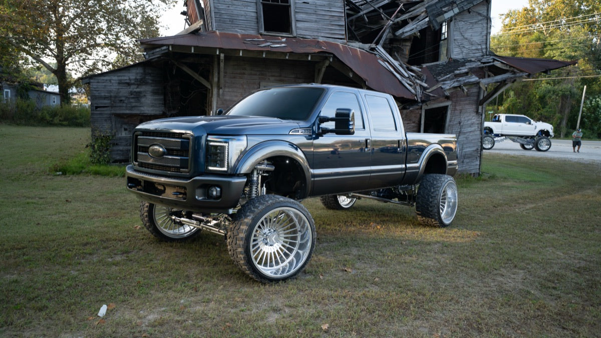 Blue Collar in front of the old barn with a second truck in the distance